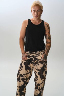 Yakışıklı genç adam kendine güvenerek duruyor, modaya uygun kıyafetler giyiyor, eşsiz tarzını vurguluyor..