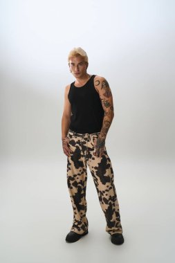 Yakışıklı genç adam, sanatsal yeteneğini sergileyerek, şık bir kıyafet içinde gururla duruyor..