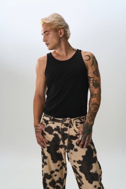 Genç bir adam, modern ve minimalist bir ortamda kendine güvenen bir şekilde poz verirken tarz yayar..