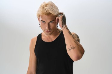 Platin saçlı genç bir adam kendine güvenerek poz verirken eşsiz bir stil sergiliyor..