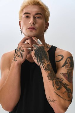 Yakışıklı genç adam dövmelerini ve moda tarzını kapalı alanda yaratıcı bir şekilde sergiliyor..