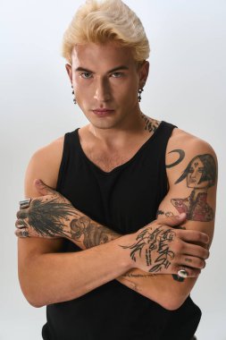 Sarı saçlı ve dövmeli genç adam kendine güvenerek, tarzıyla hava atıyor..