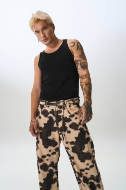 Şık genç adam sanatsal bir mekanda cesur bir tasarım içeren kıyafetini sunar..