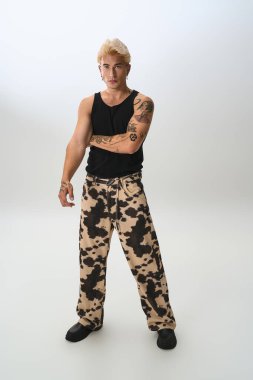 Yakışıklı genç adam modern bir stüdyo ortamında poz verirken modaya uygun kıyafetler gösteriyor..