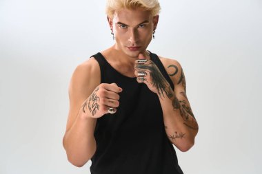 Genç adam kendine has tarzını ve tutumunu cesur dövmeleri ve çarpıcı moda seçimleriyle sergiliyor..