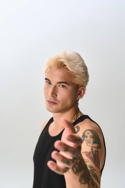 Dövmeleri olan kendine güvenen genç adam moda anlayışını göstermek için elini şık bir şekilde uzatıyor..