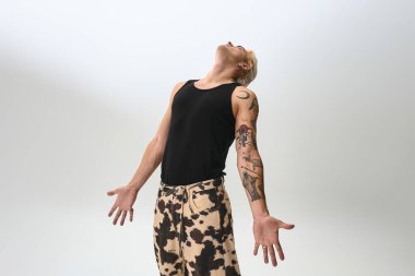 Kendine güvenen genç bir adam şık bir şekilde poz veriyor basit bir arkaplana karşı..