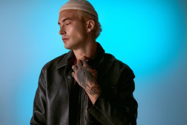 Şık bir genç adam kendine güvenerek moda kıyafetlerini ve dövmelerini sergiliyor..