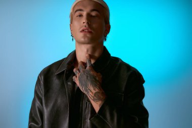 Şık bir genç adam dövmelerini ve modaya uygun kıyafetlerini gösteriyor, modern özgüven yayıyor..