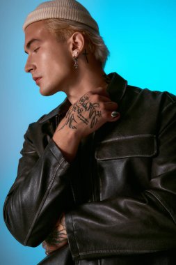 Dövmeli genç cesur mavi bir ortamda moda yeteneğini gösteriyor, kendine güveni tam..