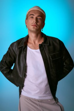 Yakışıklı genç adam kendine güvenerek poz veriyor. Modern moda kıyafetleri ve şekilli saçlar giyiyor..