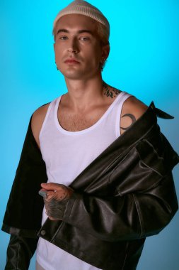 Şık bir genç adam kendine güvenerek deri bir ceket ve sıradan bir atlet giyiyor..