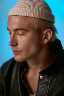 Kendine güvenen, sarı saçlı genç bir adam şık bir poz veriyor..