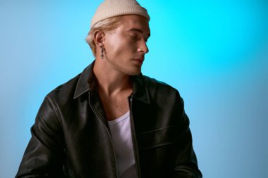 Genç ve şık bir adam zarif poz verir, şık kıyafetini ve kendine güvenen tavırlarını vurgular..