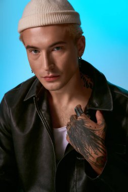 Siyah deri ceketli ve bereli genç adam benzersiz dövmelerini gösteriyor..