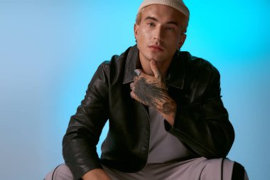 Genç bir adam şık bir ifadeyle moda anlayışını sergiliyor, şık bir şekilde oturuyor..