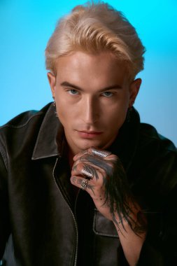 Yakışıklı genç adam kendine güveni, harmanlama tarzı ve tavırları ile serin mavi ışık altında poz verir..