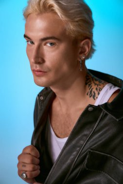 Genç bir adam şık bir deri ceketle poz verirken karizma ve tarz sergiliyor..