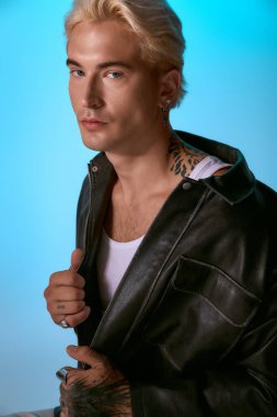 Yakışıklı genç adam kendine güveni tam bir şekilde şık bir elbiseyle poz veriyor. Benzersiz moda anlayışını vurguluyor..