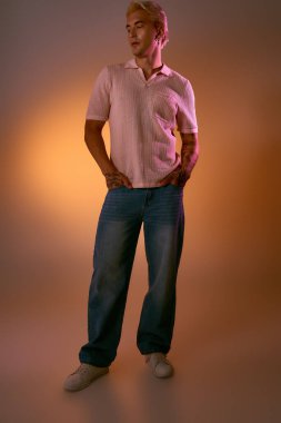Yakışıklı genç adam yumuşak bir arka plana karşı rahat bir şekilde duruyor..