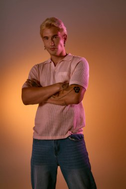 Yakışıklı genç adam kendine güvenerek poz veriyor, modaya uygun tarzını sıcak bir arkaplanda sergiliyor..