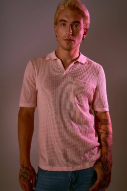 Yakışıklı genç adam, canlı renkler ve yumuşak ışıkla çevrili modaya uygun bir kıyafetle güven içinde poz veriyor..