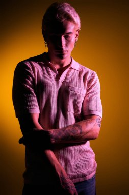 Yakışıklı genç adam kollarını kavuşturup, dövmelerini renklendiriyor..