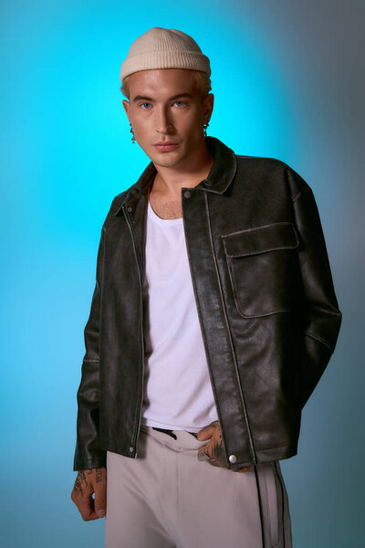 Young man in a leather jacket and beanie stands confidently, exuding modern fashion and charm.
