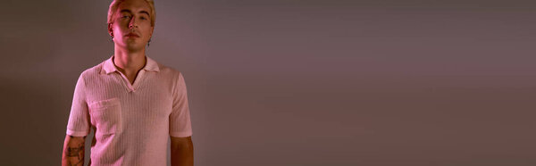 Stylish young man poses confidently in a creative studio, embodying contemporary fashion trends.