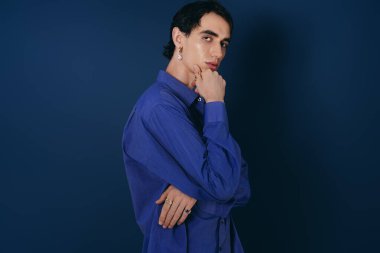 Şık mavi gömlekli yakışıklı bir adam kendine güvenen bir duruş sergiliyor..