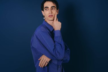 Şık mavi gömlekli yakışıklı adam düşünceli bir duruş sergiliyor..