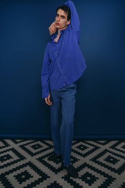 Yakışıklı bir adam çarpıcı bir arka plana karşı koyu mavi bir elbise içinde zahmetsiz bir stil sergiliyor..