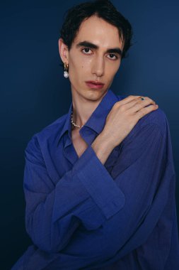 Şık mavi elbiseli kendine güvenen kişi çarpıcı bir arka plana karşı duruyor..