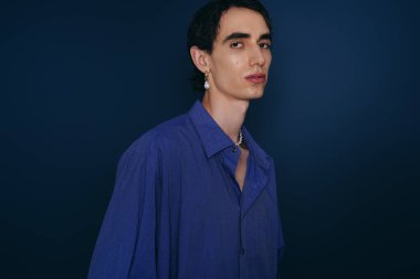 Yakışıklı bir adam kendine güveni olan mavi gömlekli, çağdaş modaya uygun bir poz verir..