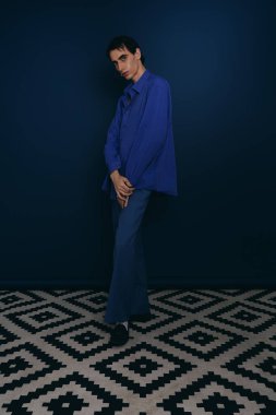 Yakışıklı bir adam kendine güvenen bir duruşla şık bir ortamda modern moda sergiliyor..