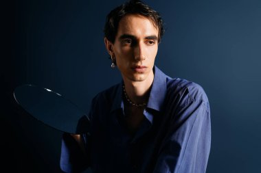 Yakışıklı adam benzersiz moda anlayışını sergiliyor, yansıtıcı tabağı kendine güvenle tutuyor..