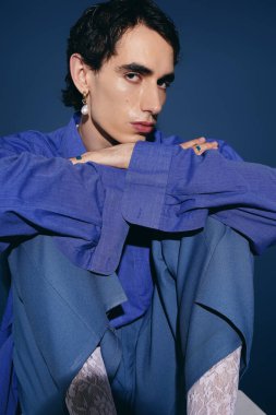 Yakışıklı adam bacak bacak üstüne atmış, eşsiz moda tarzını ve karizmasını sergiliyor..