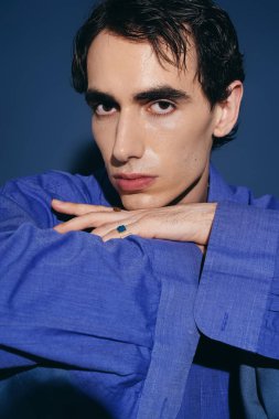 Yakışıklı genç adam şık bir moda anlayışı sergiliyor. Şık bir mavi gömlekle cesur bir poz veriyor..