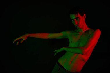 Yakışıklı adam, parlak kırmızı ve yeşil ışıklar altında sanatsal pozlar veriyor..