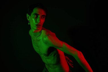 Yakışıklı adam yeşil ışık altında eşsiz bir moda sergiliyor, sanatsal bir hava yaratıyor..