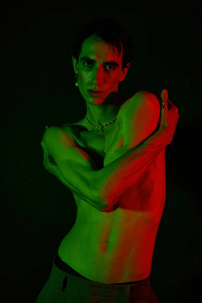 Handsome man shows off his unique style with dramatic poses under colorful lighting.