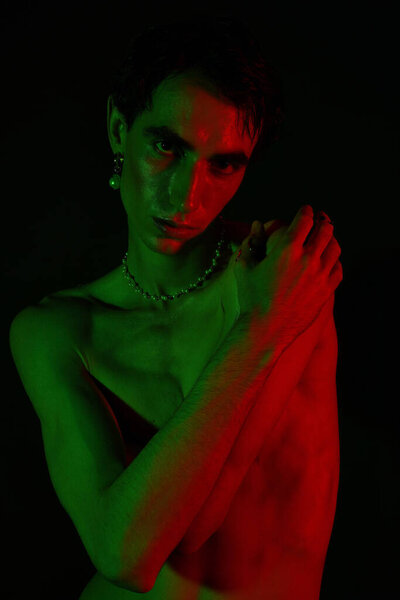 A handsome man showcases his unique style with an artistic pose under dramatic lighting.