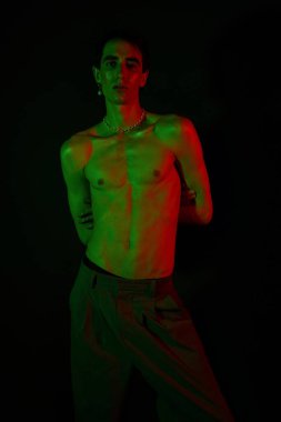 Yakışıklı bir adam yeşil ve kırmızı ışıkta poz veriyor, benzersiz tarzını sergiliyor..