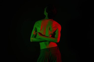 Yakışıklı adam kendini sanatsal bir yetenekle kucaklıyor, renkli ışıklarla aydınlatılıyor..