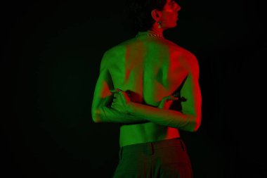 Şık bir adam dramatik ışıklandırma, ışık saçan cazibe ve kendine güvenle poz verir..