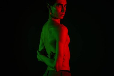 Şık bir adam kırmızı ve yeşil ışıkların altında poz verir. Benzersiz modasına dikkat çeker..