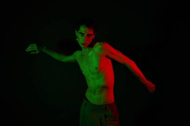 Yakışıklı bir adam canlı neon ışıklarının altında dinamik bir poz verir, kendine güvenen tarzını vurgular..