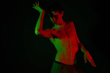 Yakışıklı bir adam dinamik bir pozla tarzını sergiliyor, parlak ışıklarla aydınlatılıyor..