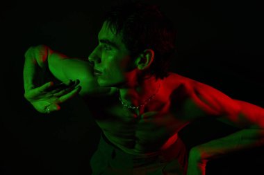 Yakışıklı bir adam renkli ışıklara karşı çarpıcı bir pozla tarzını sergiliyor..