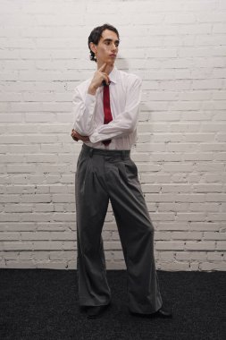 Yakışıklı bir centilmen, elleri kalçasında, zarafetle düşünceli bir şekilde ayakta durur..